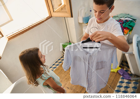Brother and sister doing laundry in a bright laundry room 118846064
