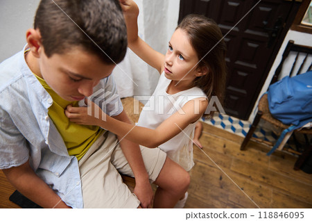 Young girl helping an unwell boy sitting indoors Young girl helping an unwell boy sitting indoors 118846095