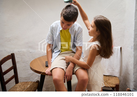 Little girl combs her older brother's hair at home Little girl combs her older brother's hair at home 118846101