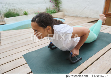 Woman practicing push-up exercise on a yoga mat outdoors for a fitness routine Woman practicing push-up exercise on a yoga mat outdoors for a fitness routine 118846226