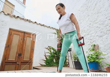 Woman practicing outdoor resistance training on wooden deck in casual athletic wear focusing on strength and fitness Woman practicing outdoor resistance training on wooden deck in casual athletic wear focusing on strength and fitness 118846233