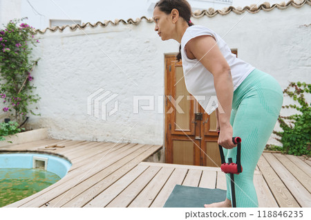 Woman exercising with resistance bands in peaceful outdoor setting focusing on strength and balance 118846235