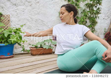 Woman practicing yoga outdoors in serene garden setting with lush green plants and peaceful atmosphere Woman practicing yoga outdoors in serene garden setting with lush green plants and peaceful atmosphere 118846272