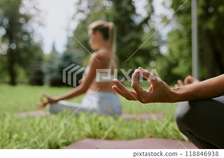 Medium close up of unrecognizable female hand during open air meditation in leafy park 118846938