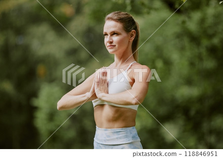 Confident young woman standing in tree pose while practicing yoga in open air 118846951
