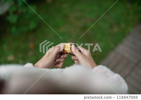 Woman peeling fresh roasted chestnut 118847008