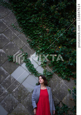 30-year-old medium-sized woman in a red muslin dress in an autumn garden 30-year-old medium-sized woman in a red muslin dress in an autumn garden 118847614