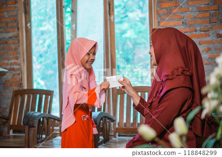 Indonesian Muslim mother gives daughter envelope of money during Eid al-Fitr celebration Indonesian Muslim mother gives daughter envelope of money during Eid al-Fitr celebration 118848299