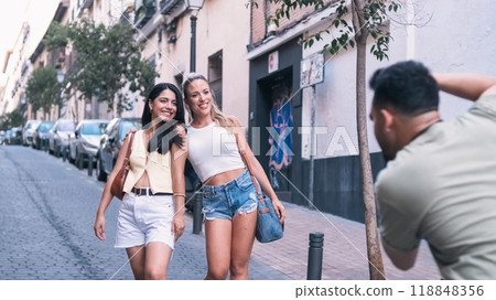Man photographing stylish female friends on city street 118848356