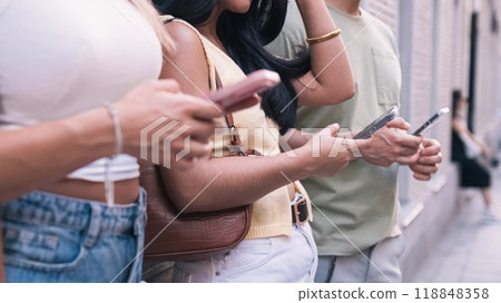 Anonymous friends using cellphones on sidewalk in city Anonymous friends using cellphones on sidewalk in city 118848358