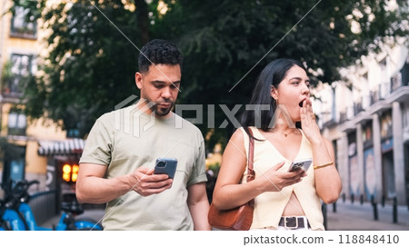 Bored couple using mobile phones on city street Bored couple using mobile phones on city street 118848410