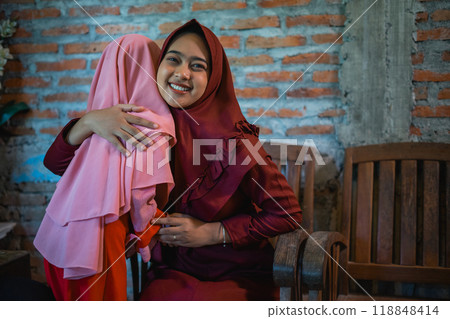 Mother embracing her little daughter during Eid al-Fitr celebration at home Mother embracing her little daughter during Eid al-Fitr celebration at home 118848414