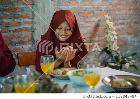 Joyful Moment at a Family Meal: A Young Girl in a Red Hijab Expresses Gratitude 118848494