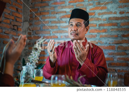 father in turban prays before eating with a Muslim family 118848535