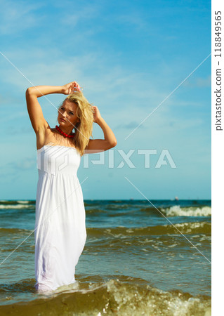 Blonde woman wearing dress walking in water 118849565