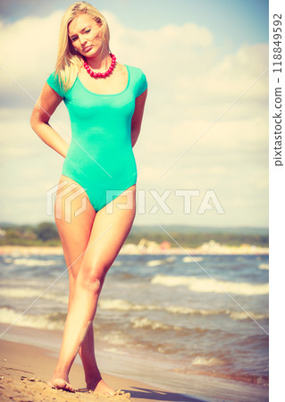 Woman walking on beach wearing swimsuit 118849592