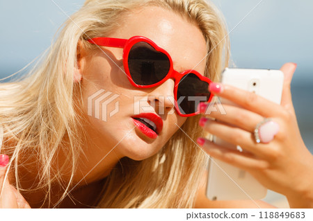 Woman lying on sandy beach using cell phone Woman lying on sandy beach using cell phone 118849683