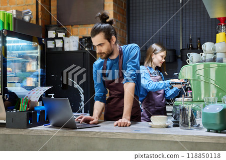Two cafe workers working together behind counter, at coffee shop 118850118