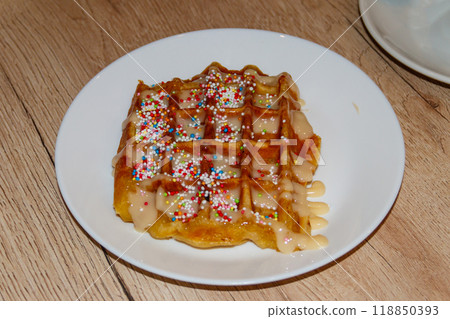 Belgian waffle with sweet toppings and white chocolate on wooden table 118850393