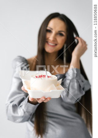 Birthday smiling woman is holding a cake in a plastic container 118850688