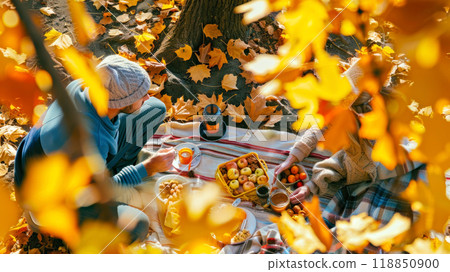 Autumn picnic with friends sharing warm drinks and treats among colorful leaves 118850900