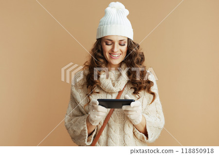 happy woman against beige sending text message using phone happy woman against beige sending text message using phone 118850918