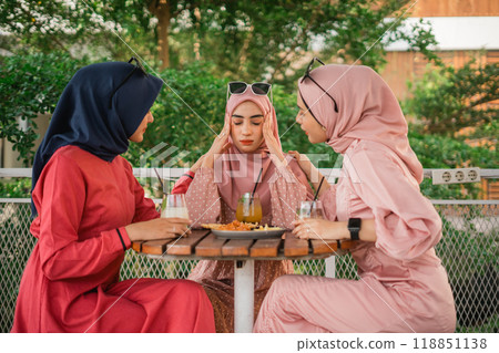 Three Women in Hijabs Engaged in Thoughtful Conversation at a Caf 118851138