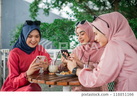 Friends enjoy coffee and use their phones at a cozy outdoor cafe on a nice afternoon 118851166