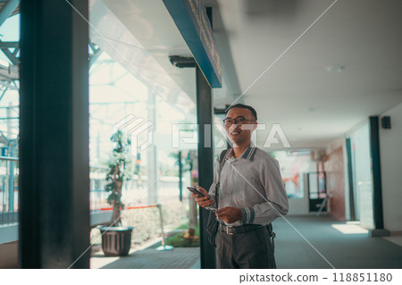 A Professional Man Holding a Phone in a Modern Urban Setting with Style and Confidence 118851180