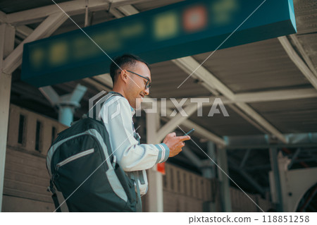 A traveler with a smartphone and backpack captures urban adventure at a busy station A traveler with a smartphone and backpack captures urban adventure at a busy station 118851258