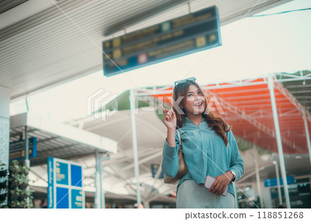 A travel enthusiast at the airport shows a cheerful expression amidst signage 118851268
