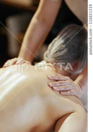 Massage therapist in massage cabinet massaging clients back 118851319