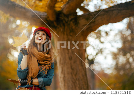 happy trendy woman in jeans shirt and red hat with autumn leaf happy trendy woman in jeans shirt and red hat with autumn leaf 118851518