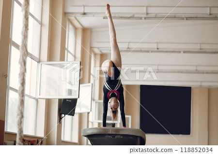 Child gymnastics balance beam. Girl gymnast athlete during an exercise horizontal bar in gymnastics competitions. Child gymnastics balance beam. Girl gymnast athlete during an exercise horizontal bar in gymnastics competitions. 118852034