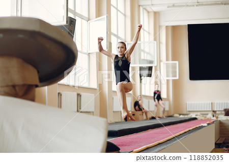 Child gymnastics balance beam. Girl gymnast athlete during an exercise horizontal bar in gymnastics competitions. Child gymnastics balance beam. Girl gymnast athlete during an exercise horizontal bar in gymnastics competitions. 118852035