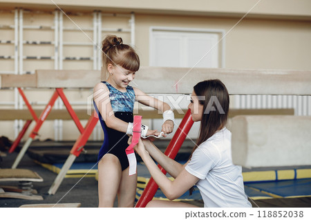 Coach with student. Girls gymnasts, performs various gymnastic exercises and jumping. Childs and sport, a healthy lifestyle. Coach with student. Girls gymnasts, performs various gymnastic exercises and jumping. Childs and sport, a healthy lifestyle. 118852038
