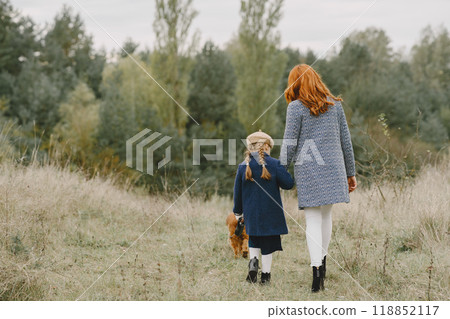 Mother and her daughter playing with dog. Family in autumn park. Pet, domestic animal and lifestyle concept. Autumn time. Mother and her daughter playing with dog. Family in autumn park. Pet, domestic animal and lifestyle concept. Autumn time. 118852117