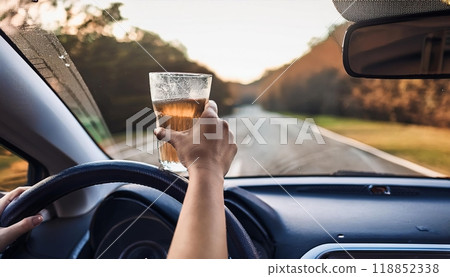 A driver raises a glass of beverage while steering along a winding road during sunset in a scenic countryside area. Generative AI 118852338