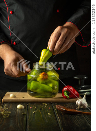 A cook manually fills a jar with bell pepper before preserving them with spices in a jar. The concept of pickling delicious bell peppers with spices A cook manually fills a jar with bell pepper before preserving them with spices in a jar. The concept of pickling delicious bell peppers with spices 118852346