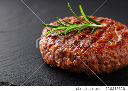 Juicy and aromatic burger patty on a board, decorated with a sprig of rosemary, space for a healthy food concept Juicy and aromatic burger patty on a board, decorated with a sprig of rosemary, space for a healthy food concept 118852810