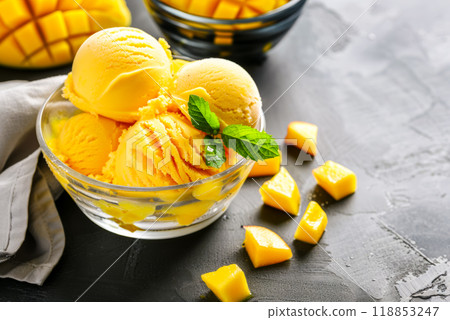 Mango ice cream in a glass bowl on a gray table, decorated with a mint leaf, vegetarian dessert 118853247