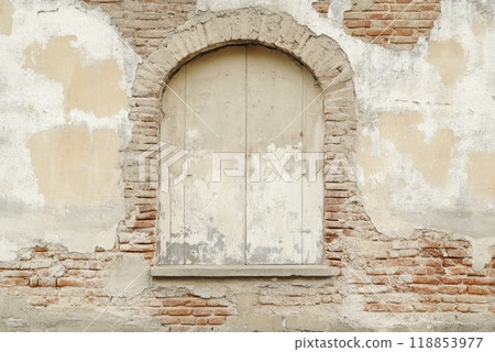 Old rustic wall with an arched window and weathered bricks showcasing peeling paint and a vintage feel in a historic setting 118853977