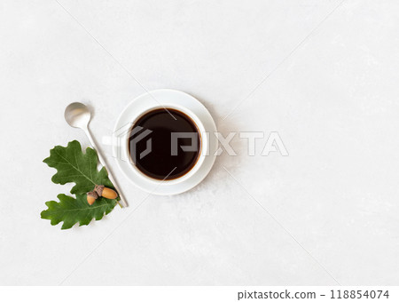Black coffee with acorns on white background. Acorn coffee in a white cup with copy space. Top view, flat lay. Black coffee with acorns on white background. Acorn coffee in a white cup with copy space. Top view, flat lay. 118854074
