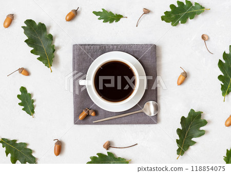 Autumn still life with black coffee on a grey napkin with acorns and leaves. Acorn coffee on white background. Top view, flat lay. Autumn still life with black coffee on a grey napkin with acorns and leaves. Acorn coffee on white background. Top view, flat lay. 118854075