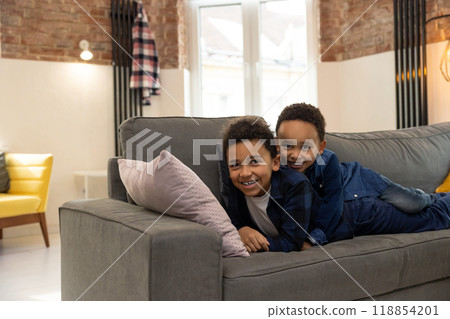 Cheerful kids lying together on sofa and having fun at home 118854201
