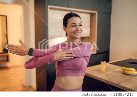 Young woman dressed in pink sportswear performing yoga stretches to improve strength Young woman dressed in pink sportswear performing yoga stretches to improve strength 118854215