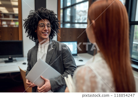 Two colleagues talking in the office and looking involved Two colleagues talking in the office and looking involved 118854247