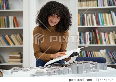 Cute young caucasian dark-haired woman in the library looking busy and involved Cute young caucasian dark-haired woman in the library looking busy and involved 118854292