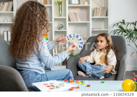 Female speech therapist with long hair working with a cute girl 118854329