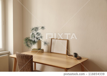 Christmas Scandinavian interior. Winter home decor. Blank horizontal wooden picture frame mockup, cup of coffee, tea. Table, rattan chair at window. Pine tree branches, vase. Wall background 118854339